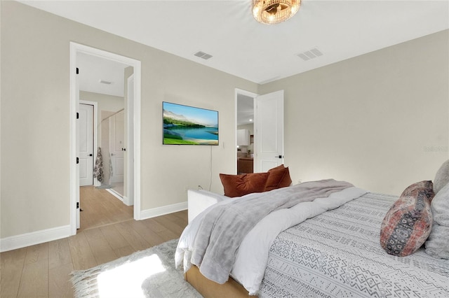 bedroom featuring connected bathroom and light hardwood / wood-style floors