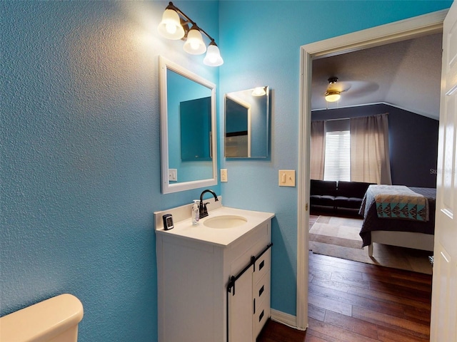 bathroom featuring hardwood / wood-style floors, lofted ceiling, vanity, toilet, and ceiling fan