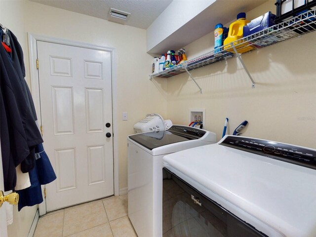 laundry area with separate washer and dryer and light tile patterned floors