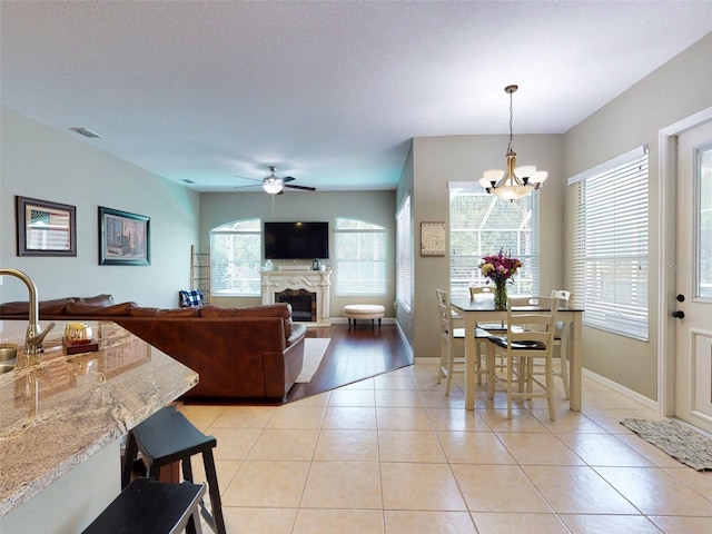 tiled dining space featuring a textured ceiling and ceiling fan with notable chandelier