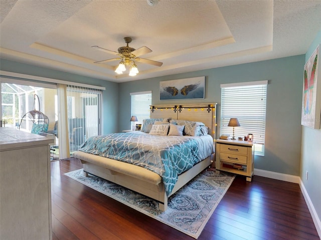 bedroom featuring dark hardwood / wood-style floors, ceiling fan, and a raised ceiling