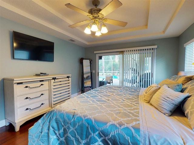 bedroom featuring ceiling fan, a raised ceiling, access to outside, and multiple windows