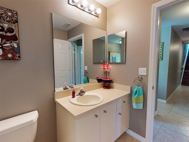 bathroom with toilet, vanity, and tile patterned flooring