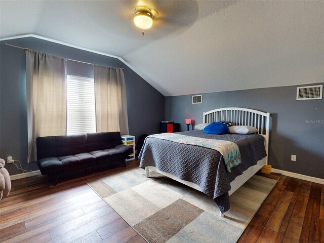 bedroom featuring ceiling fan, hardwood / wood-style floors, lofted ceiling, and a textured ceiling