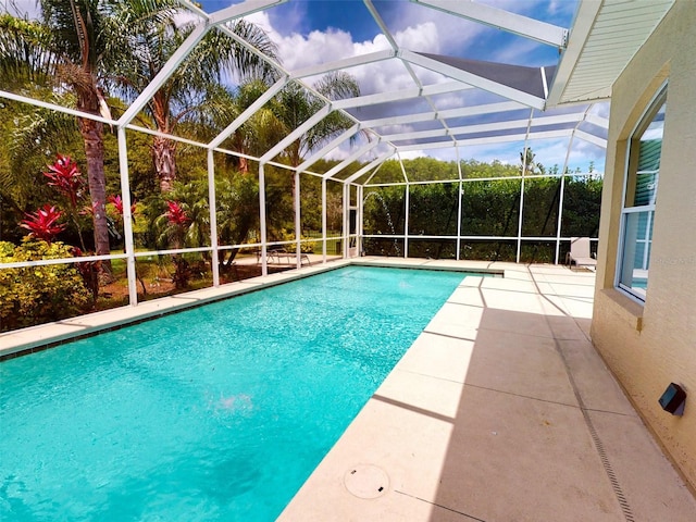 view of swimming pool with glass enclosure and a patio