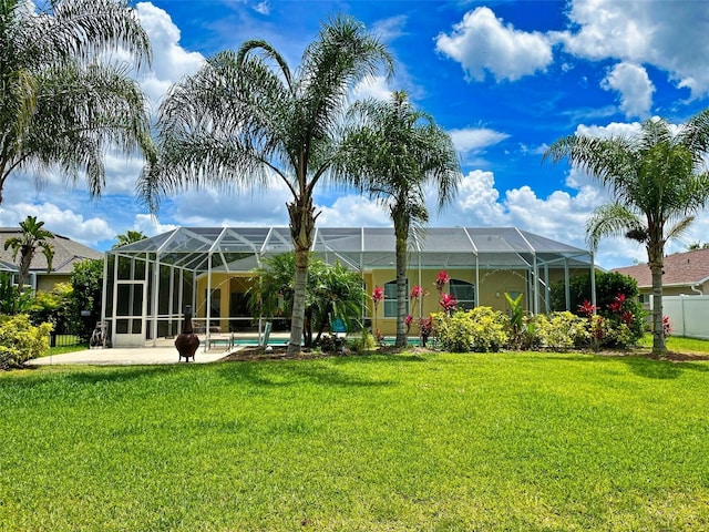 back of property with a yard and glass enclosure