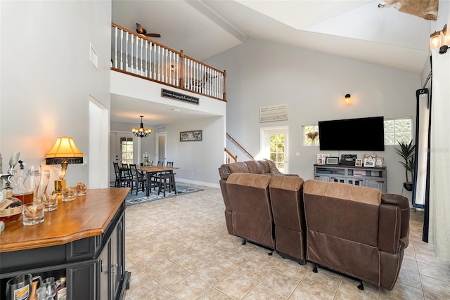 tiled living room featuring high vaulted ceiling, a healthy amount of sunlight, and ceiling fan with notable chandelier