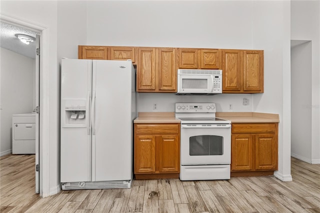 kitchen with light hardwood / wood-style floors, white appliances, a textured ceiling, and washer / clothes dryer