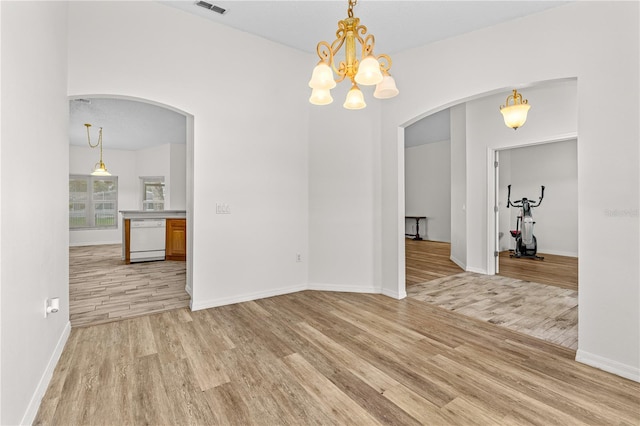 unfurnished dining area with a notable chandelier and light wood-type flooring