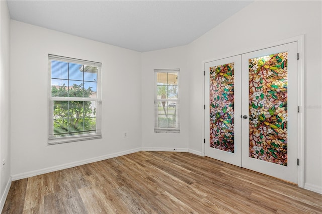 empty room with french doors, light wood-type flooring, and a healthy amount of sunlight