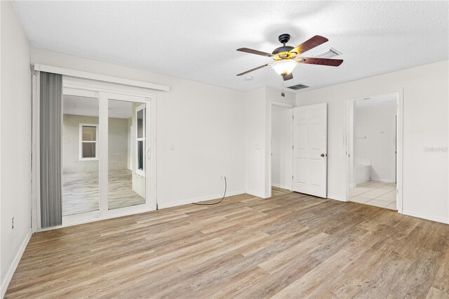 unfurnished bedroom with a textured ceiling, ceiling fan, ensuite bathroom, and light hardwood / wood-style flooring