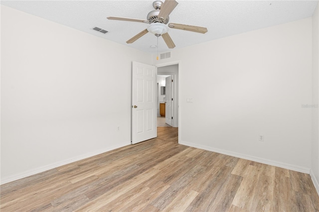 empty room with ceiling fan, a textured ceiling, and light hardwood / wood-style flooring