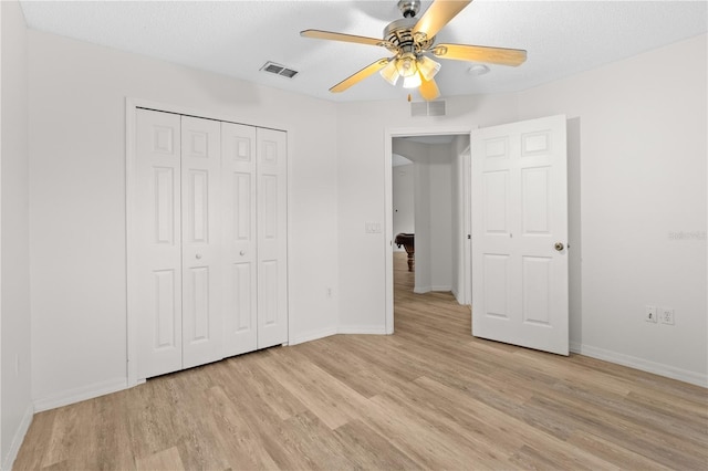 unfurnished bedroom featuring a textured ceiling, a closet, light hardwood / wood-style flooring, and ceiling fan