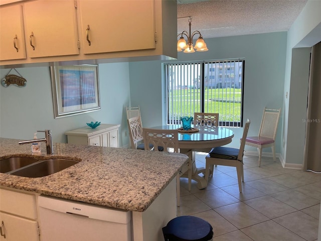 kitchen with white dishwasher, sink, light tile patterned floors, decorative light fixtures, and a notable chandelier