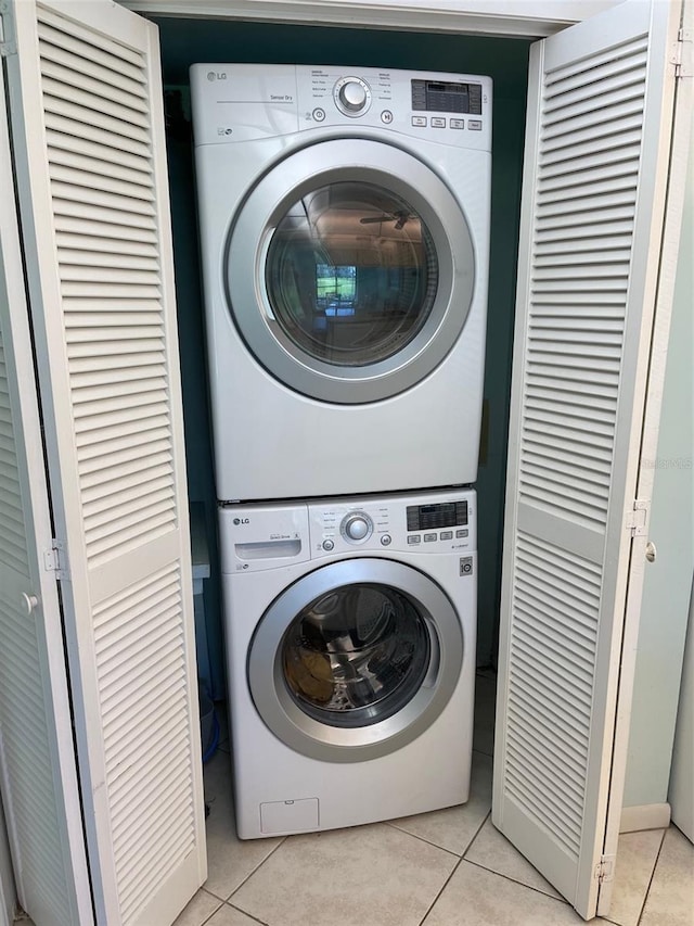 laundry room with stacked washer / dryer and light tile patterned floors