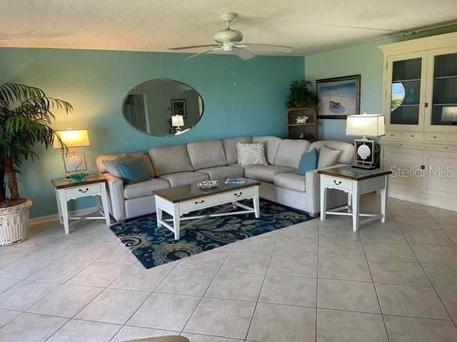 tiled living room with ceiling fan and a textured ceiling