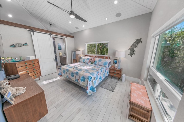 bedroom featuring wooden ceiling, ensuite bathroom, ceiling fan, a barn door, and light wood-type flooring