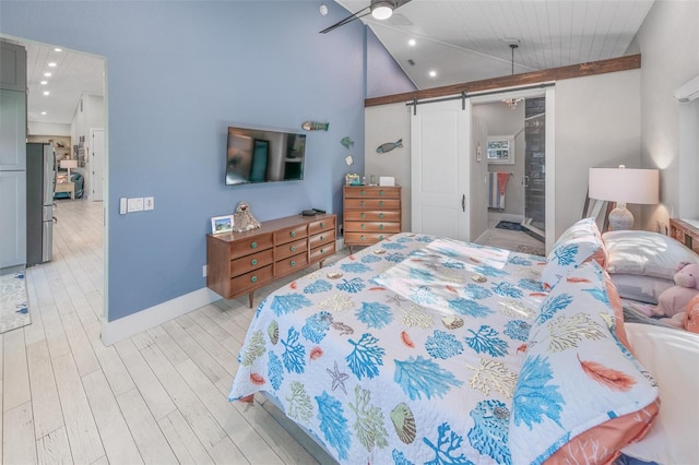 bedroom featuring stainless steel refrigerator, a barn door, light hardwood / wood-style floors, and vaulted ceiling