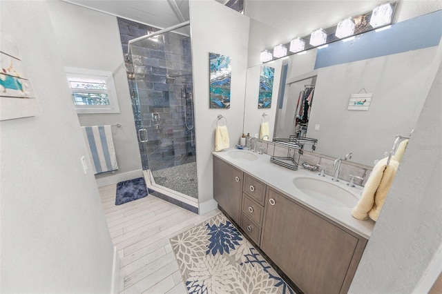 bathroom featuring a shower with door and vanity