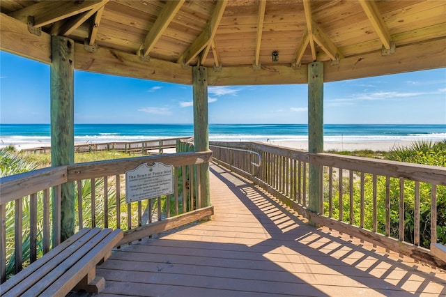 wooden terrace featuring a gazebo, a water view, and a view of the beach