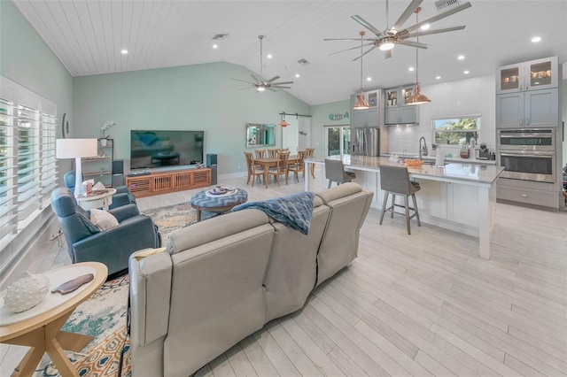 living room featuring high vaulted ceiling, sink, light hardwood / wood-style flooring, ceiling fan, and wood ceiling