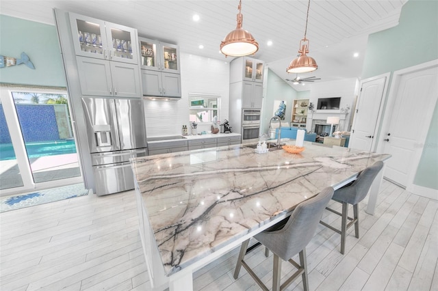 kitchen featuring light stone countertops, a spacious island, decorative light fixtures, and appliances with stainless steel finishes