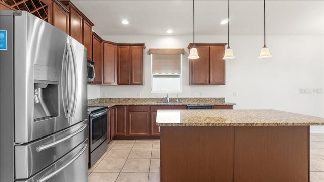 kitchen featuring light stone countertops, appliances with stainless steel finishes, sink, pendant lighting, and a center island