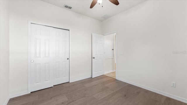 unfurnished bedroom with ceiling fan, light wood-type flooring, and a closet