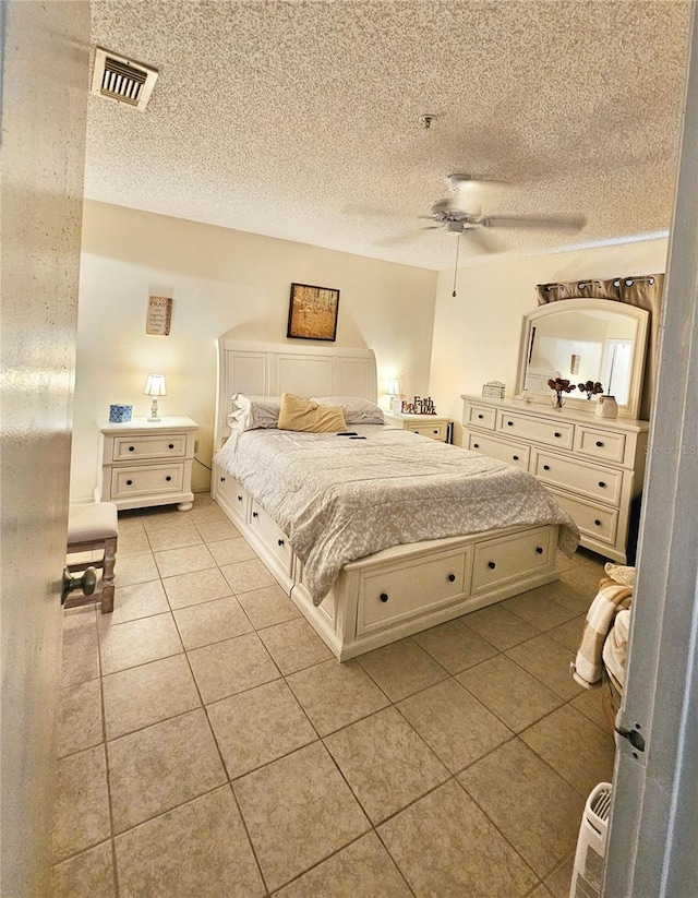 tiled bedroom with ceiling fan and a textured ceiling