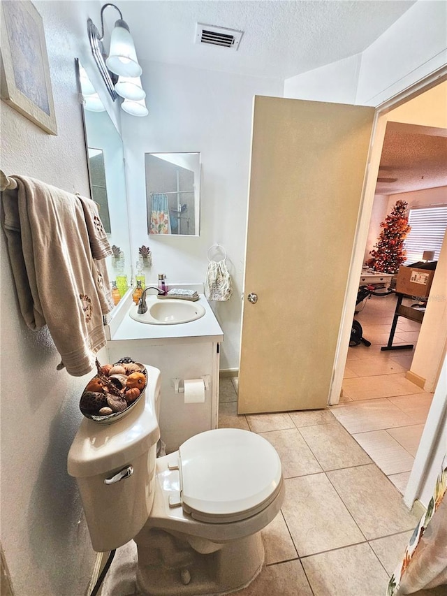 bathroom featuring tile patterned floors, vanity, toilet, and a textured ceiling