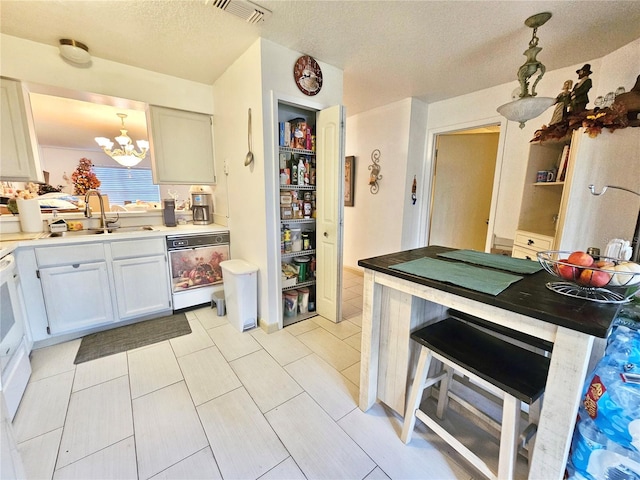 kitchen featuring white cabinetry, dishwasher, a notable chandelier, a textured ceiling, and decorative light fixtures