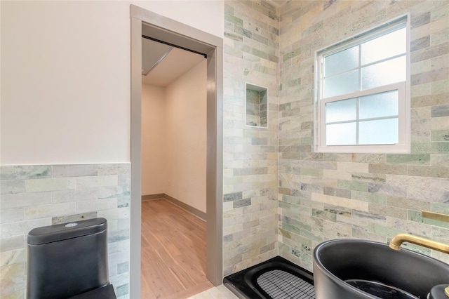 bathroom featuring hardwood / wood-style flooring, tile walls, and toilet