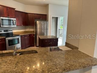 kitchen featuring light stone counters, sink, and appliances with stainless steel finishes