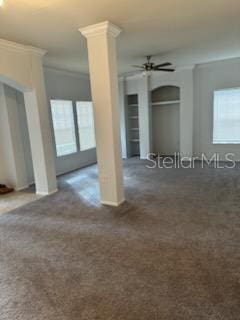 spare room featuring ceiling fan, dark carpet, crown molding, and decorative columns