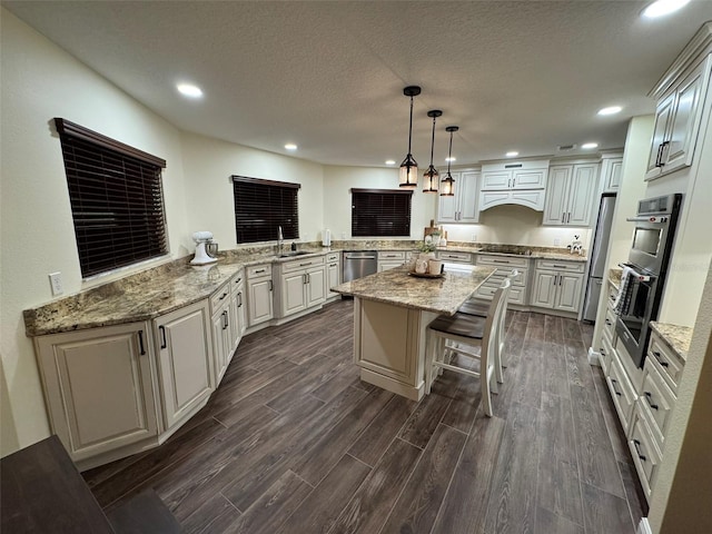 kitchen with a breakfast bar, sink, hanging light fixtures, kitchen peninsula, and light stone countertops