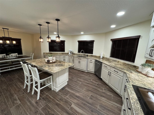 kitchen with a breakfast bar, sink, white cabinetry, stainless steel dishwasher, and kitchen peninsula