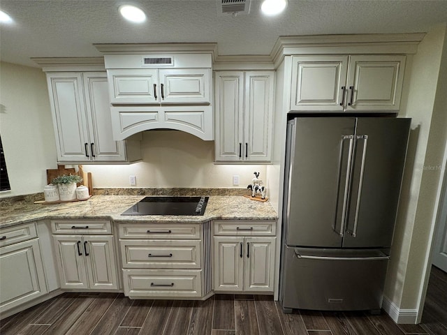 kitchen with black electric cooktop, high end fridge, light stone counters, and white cabinets