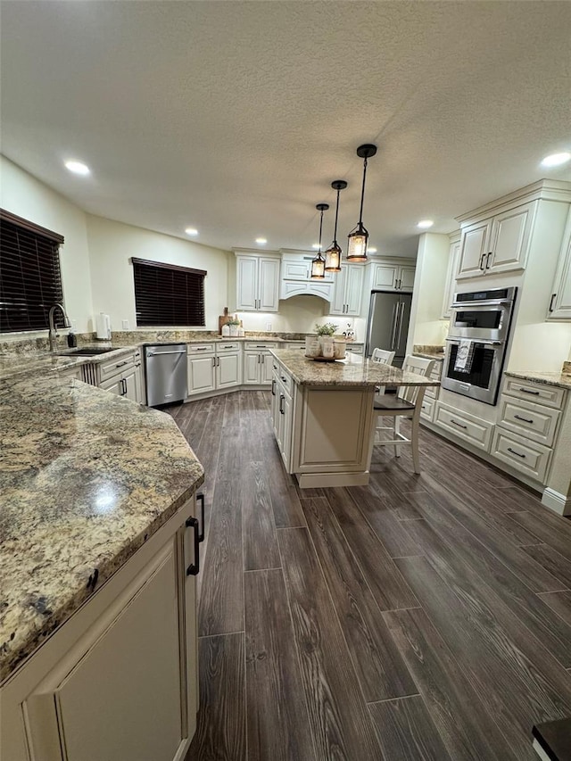 kitchen featuring sink, hanging light fixtures, a kitchen breakfast bar, stainless steel appliances, and a kitchen island