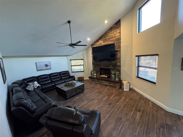 living room featuring ceiling fan, a stone fireplace, high vaulted ceiling, and a textured ceiling