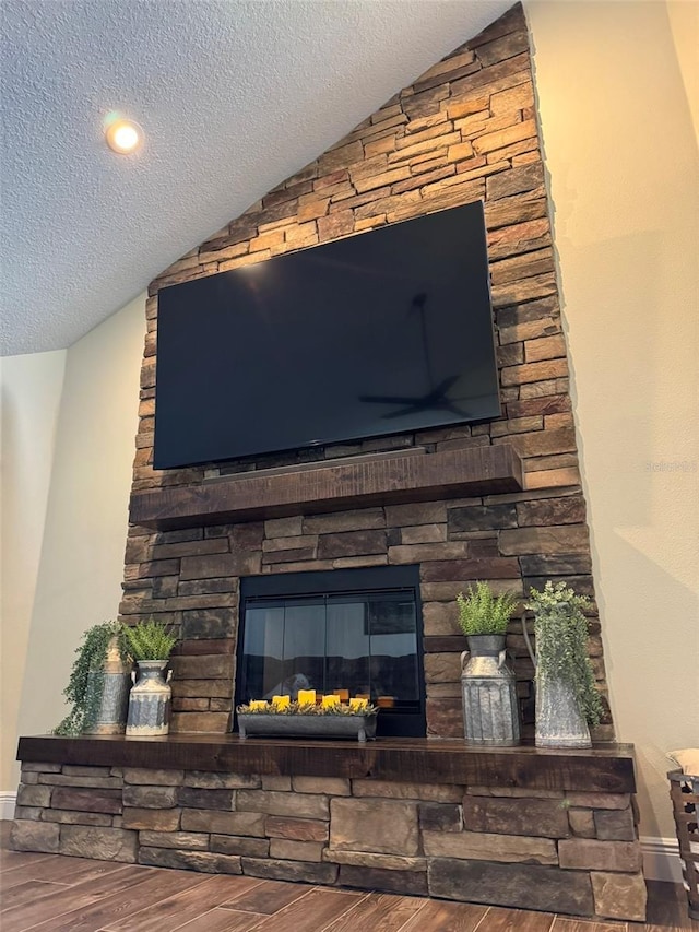 room details featuring hardwood / wood-style floors, a stone fireplace, and a textured ceiling