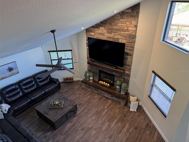 living room with ceiling fan, a fireplace, vaulted ceiling, and a textured ceiling