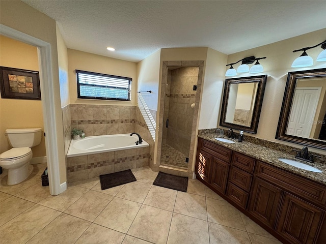 bathroom featuring tile patterned flooring, a stall shower, a textured ceiling, and a sink