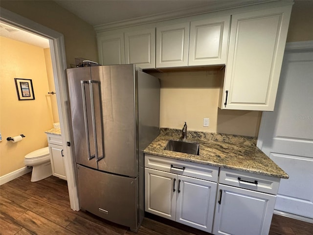 kitchen featuring sink, high end fridge, white cabinetry, light stone counters, and dark hardwood / wood-style flooring