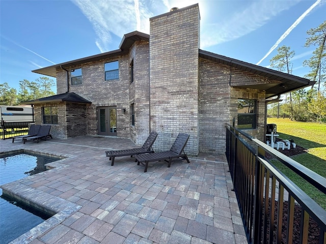 back of house with a fenced in pool, a patio, and french doors