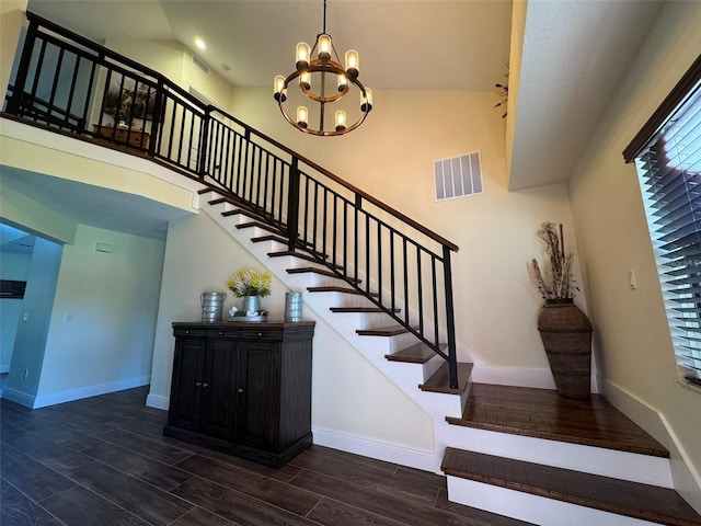 staircase featuring visible vents, wood finished floors, a high ceiling, an inviting chandelier, and baseboards