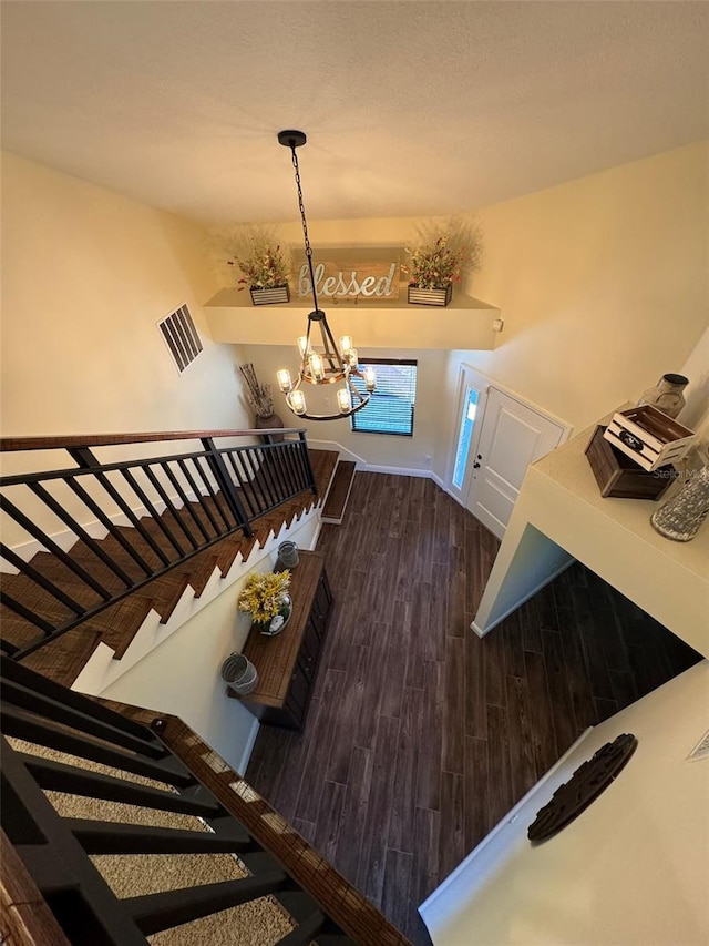 foyer entrance with visible vents, dark wood-type flooring, baseboards, stairway, and a notable chandelier