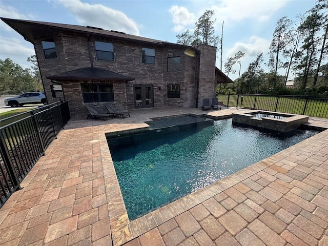 view of pool with fence, a pool with connected hot tub, and a patio area