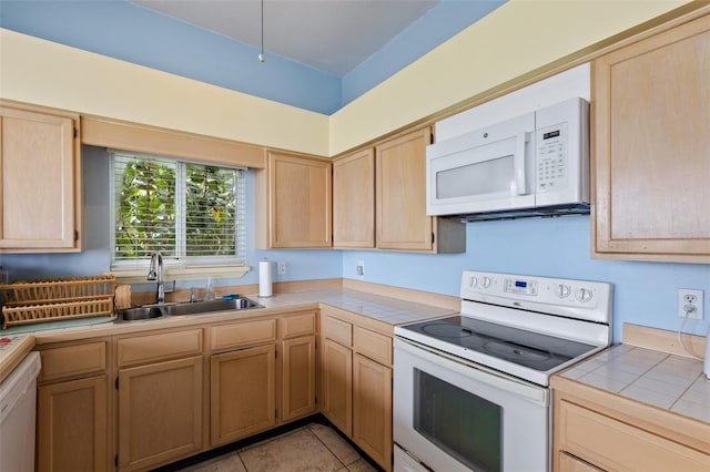 kitchen featuring tile counters, sink, white appliances, light brown cabinetry, and light tile patterned flooring