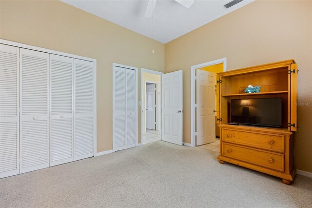 unfurnished bedroom featuring light carpet, two closets, and ceiling fan