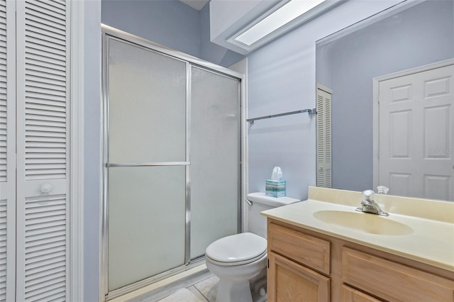 bathroom featuring vanity, tile patterned floors, a skylight, toilet, and a shower with shower door